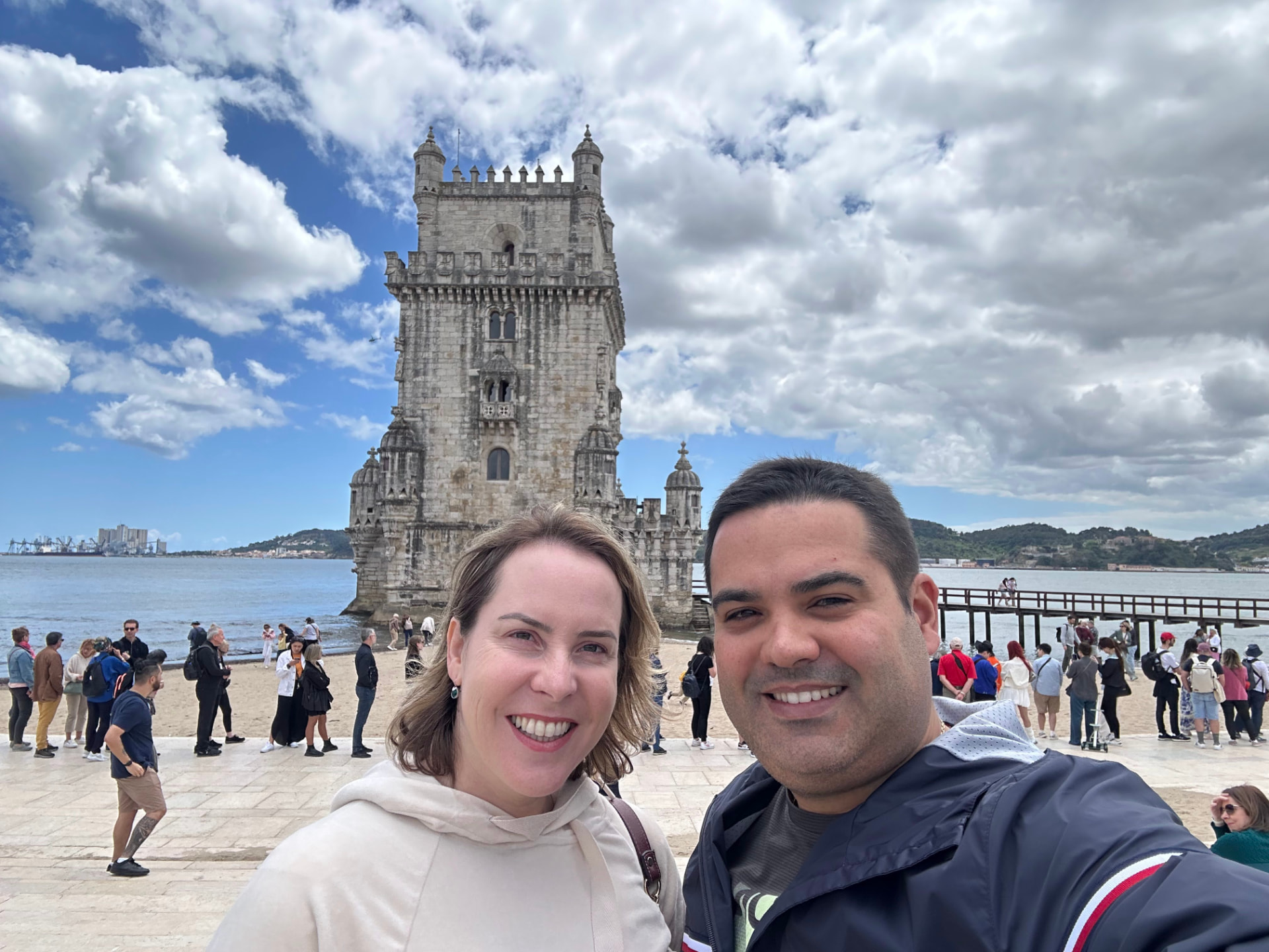 Casal em viagem diante da Torre de Belém, em Lisboa